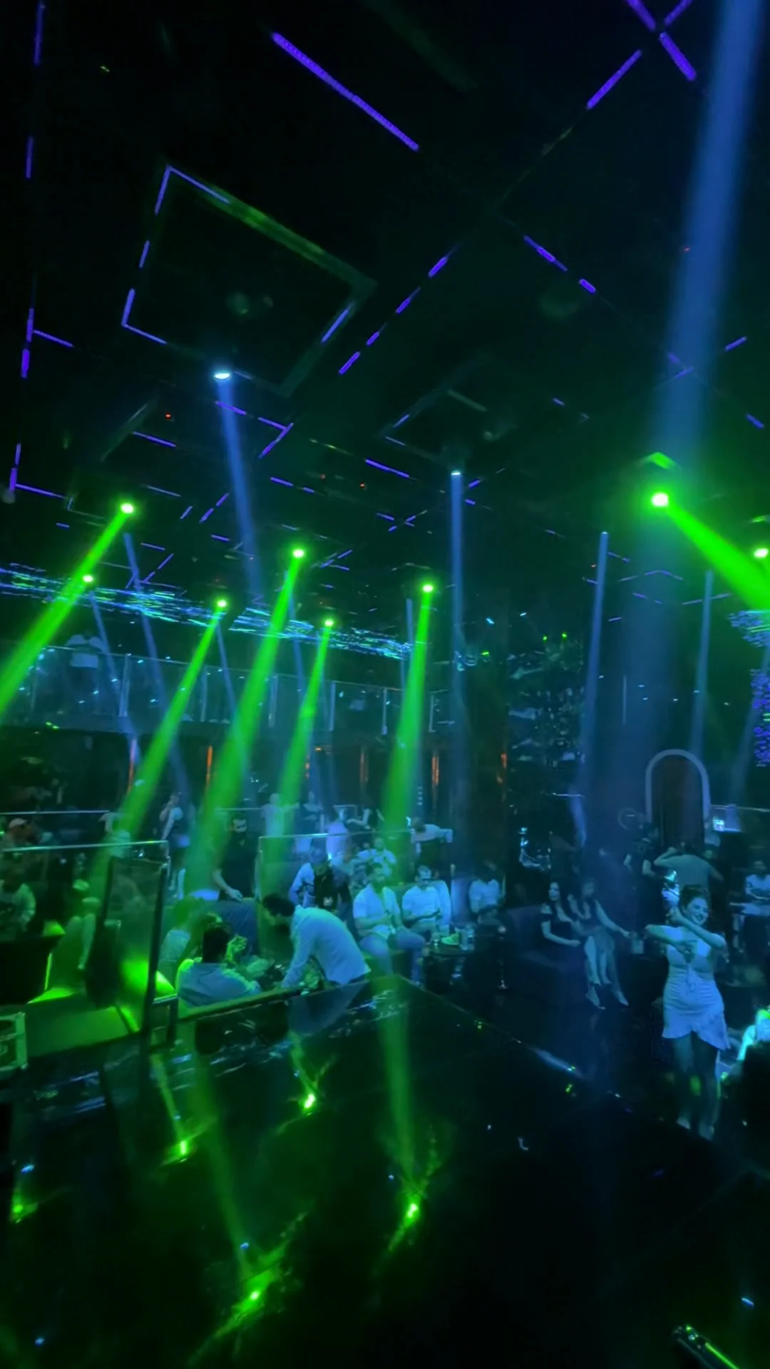 Geometric kinetic ceiling light grid with green spotlight shafts cutting through the room at XOXO Nightclub & Lounge Dubai