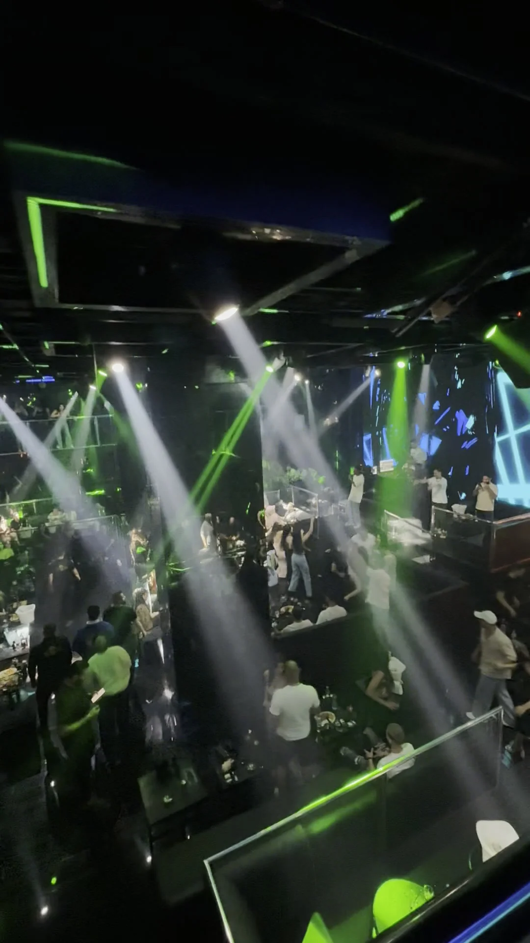 Focused spotlight shafts cutting through haze over guests celebrating on the dancefloor at XOXO Nightclub & Lounge Dubai