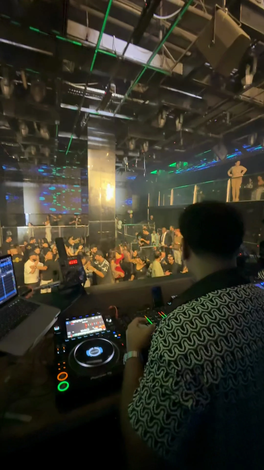 Over-the-shoulder DJ view from behind the decks looking out over the packed dancefloor at XOXO Nightclub & Lounge Dubai