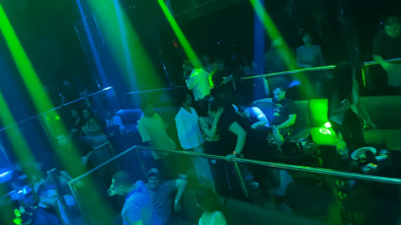 Dynamic emerald green laser arrays cutting across the mezzanine crowd at XOXO Nightclub & Lounge Dubai