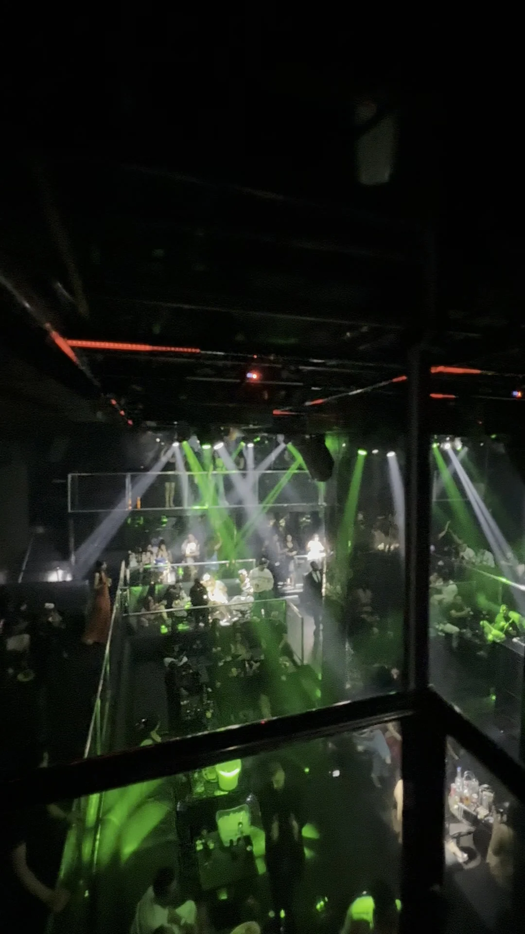 Elevated perspective from the glass mezzanine railing overlooking the dancefloor and glowing VIP tables at XOXO Nightclub & Lounge Dubai