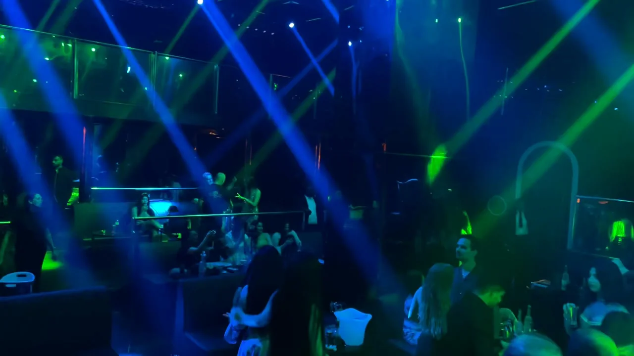 VIP banquette tables with illuminated ice buckets and socialising guests under blue spotlight shafts at XOXO Nightclub & Lounge Dubai